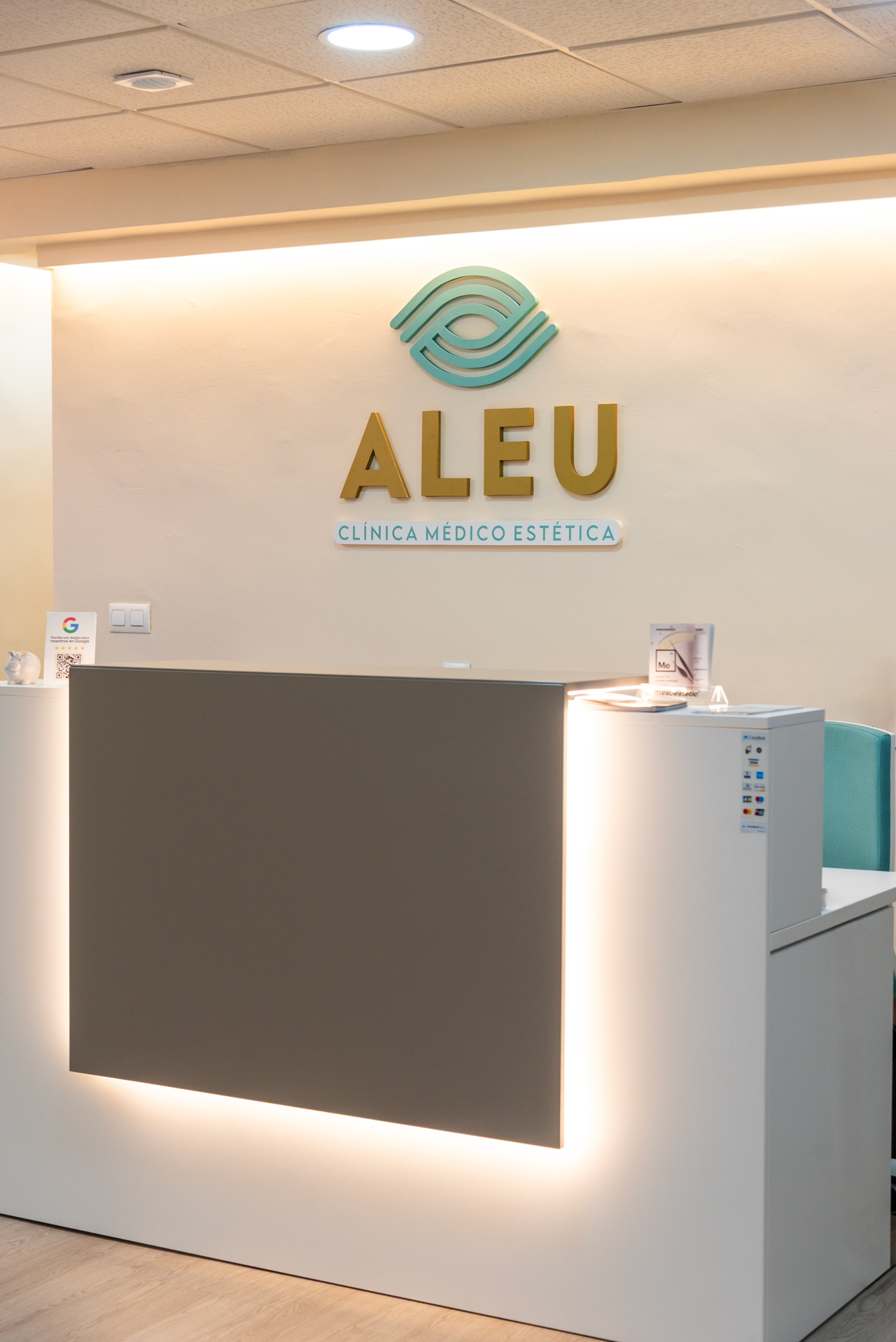 Recepción de Clínica Aleu con mostrador de atención al paciente en un ambiente elegante y profesional.